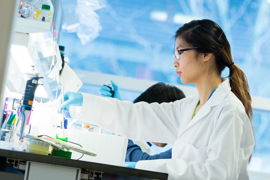 Person wearing a white coat working in a laboratory.